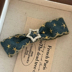 Detailed macro view of denim bow hair clip with gold stars and silver rhinestone star