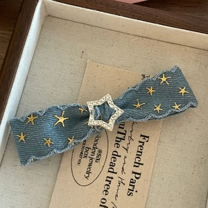 Detail of denim star hair clip with crystals inside a wooden vintage jewelry box