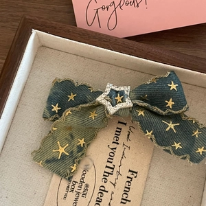 Vintage denim bow hair clip with gold stars and rhinestone center in a wooden box