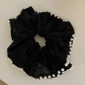 Close-up of black mesh scrunchie with white pearl trim and delicate floral texture