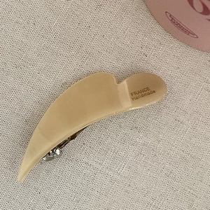 Detail of cream acetate hair clip with silver metal spring and handmade engraving
