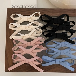 Detail of ribbed bow hair clips in cream, black, pink and blue within a wooden display box
