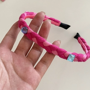 Detail of pink woven headband with blue faux gemstones and comfortable black fabric ends