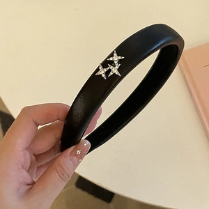 Detail of a black faux leather headband featuring three silver star accents with rhinestones