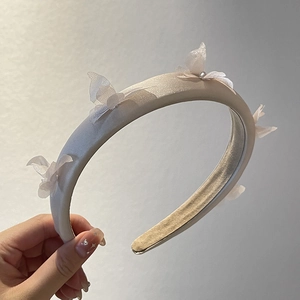 Close-up of champagne satin headband featuring organza butterflies and pearls
