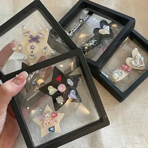 Detalle de pinzas para el cabello Y2K con diamantes rosas en cajas de película negra