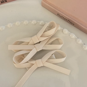 Set of two cream bow hair clips with long ribbons on a decorative white pearl plate
