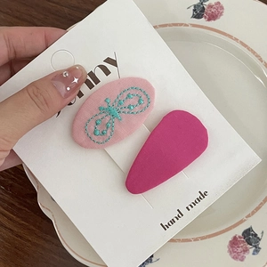 Détail de barrettes à cheveux en tissu rose avec nœud brodé et pince couleur magenta
