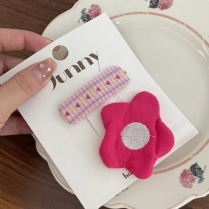 Détail de pinces à cheveux à fleurs et carreaux roses pour filles sur carte