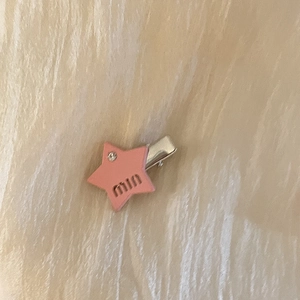 Détail d'une barrette étoile rose avec gravure min et un petit strass brillant incrusté