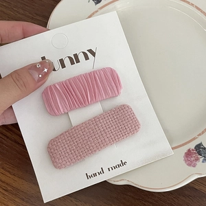 Détail de pinces à cheveux en tissu rose plissé et tweed sur carte artisanale