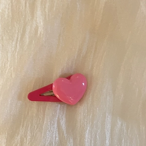 Vue détaillée d'une pince à cheveux rose en forme de cœur avec surface en résine lisse