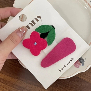 Détail de barrettes BB brodées de fleurs sur une carte de présentation blanche
