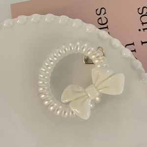 Close-up of a pearlescent white telephone wire hair tie with a creamy bow decoration