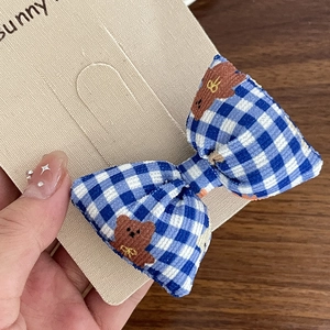 Détail d'une pince à cheveux à nœud vichy bleu et blanc avec broderie petit ours