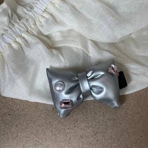 Silver bow hair clip with pink rhinestones and pearl embellishment on fabric