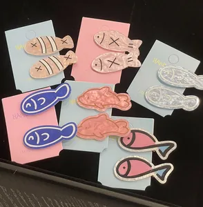 Close-up of colorful fish and dolphin hair clips with glossy marble texture on card