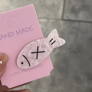 Close-up of a pink marble pattern fish-shaped hair clip on a decorative card display