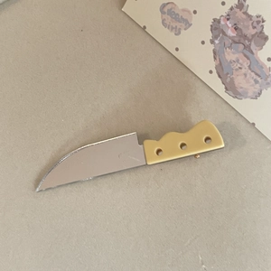 Detailed macro view of a creative knife-shaped hair clip with silver acrylic blade and yellow handle