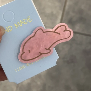 Detail shot of a cute pink resin dolphin hair clip on a blue handmade display card
