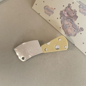 Detail shot of creative knife hair clip with silver blade and cheese-style yellow handle