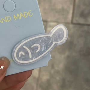 Close-up of cute blue marble acrylic fish hair clip on hand-made packaging card