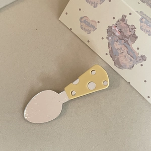 Detail of cheese-style spoon hair clip with yellow polka dot handle and silver mirror finish