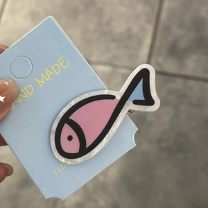 Close-up of cute pink fish hair clip on hand-made card with blue background