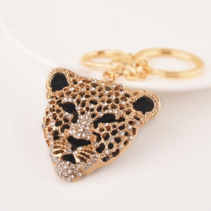 Golden leopard head keychain with sparkling rhinestones and black enamel accents on a plate