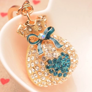 Porte-clés sac de fortune doré avec strass et nœud bleu dans une assiette en cœur
