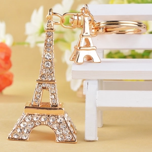 Porte-clés Tour Eiffel doré serti de strass avec fermoir mousqueton sur un petit banc blanc