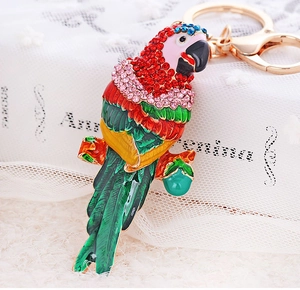Détail d'un porte-clés perroquet coloré serti de strass avec boucle dorée sur dentelle