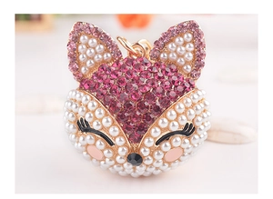 Détail d'un porte-clés renard mignon avec strass violets et perles blanches