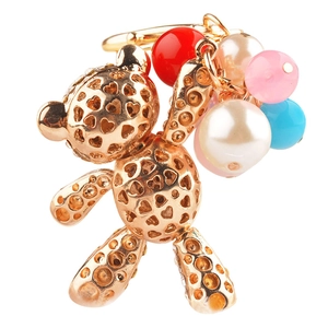 Golden hollow bear keychain with heart cutouts and colorful beads on white background