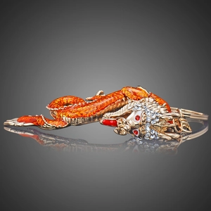 Macro shot of orange enamel dragon keychain with gold edges and sparkling crystals