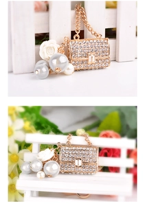 Detailed view of golden alloy purse keychain with sparkling rhinestones and white rose charm