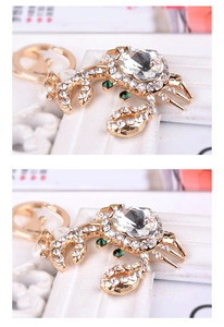 Detail of a golden crab keychain with heart-shaped crystal and white rhinestones