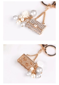 Detail of golden alloy keychain with rhinestone mini handbag and elegant faux pearls