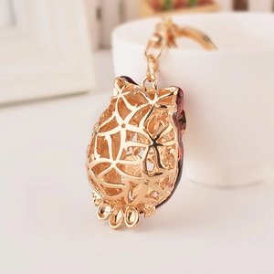Goldener Eulen-Schlüsselanhänger mit Opal und rotem Emaille an einer weißen Tasse