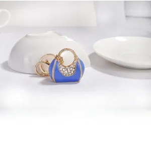 Detail of blue enamel handbag keychain with gold trim and sparkling white rhinestones