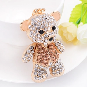 Sparkling crystal encrusted teddy bear keychain in gold metal finish with floral accent