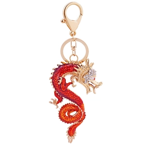 Exquisite golden dragon keychain with red enamel and crystals on a white background
