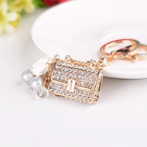 Elegant rhinestone handbag keychain with pearls and floral charms on a gold base