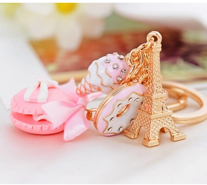 Detailed macro of pink macaron and golden Eiffel Tower charms on a keychain