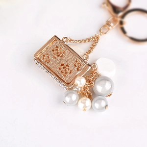 Fashionable golden pearl keychain featuring embossed roses and rhinestones on a metal plate