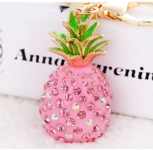 Macro view of pink crystal pineapple keychain with green enamel leaves and gold clasp
