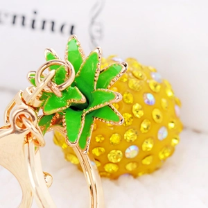 Macro detail of golden resin pineapple keychain with yellow crystals and green leaves
