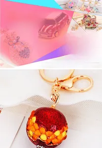 Close-up of golden keychain featuring red pomegranate fruit and crystal perfume bottle