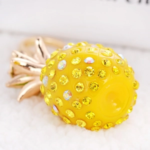 Macro shot of yellow resin pineapple keychain charm with shimmering crystal rhinestones