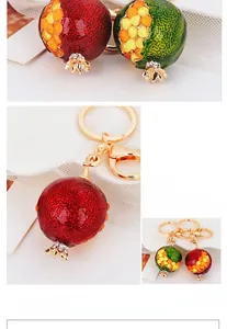 Detailed close-up of cute pomegranate metal keychain with red enamel and white rhinestones